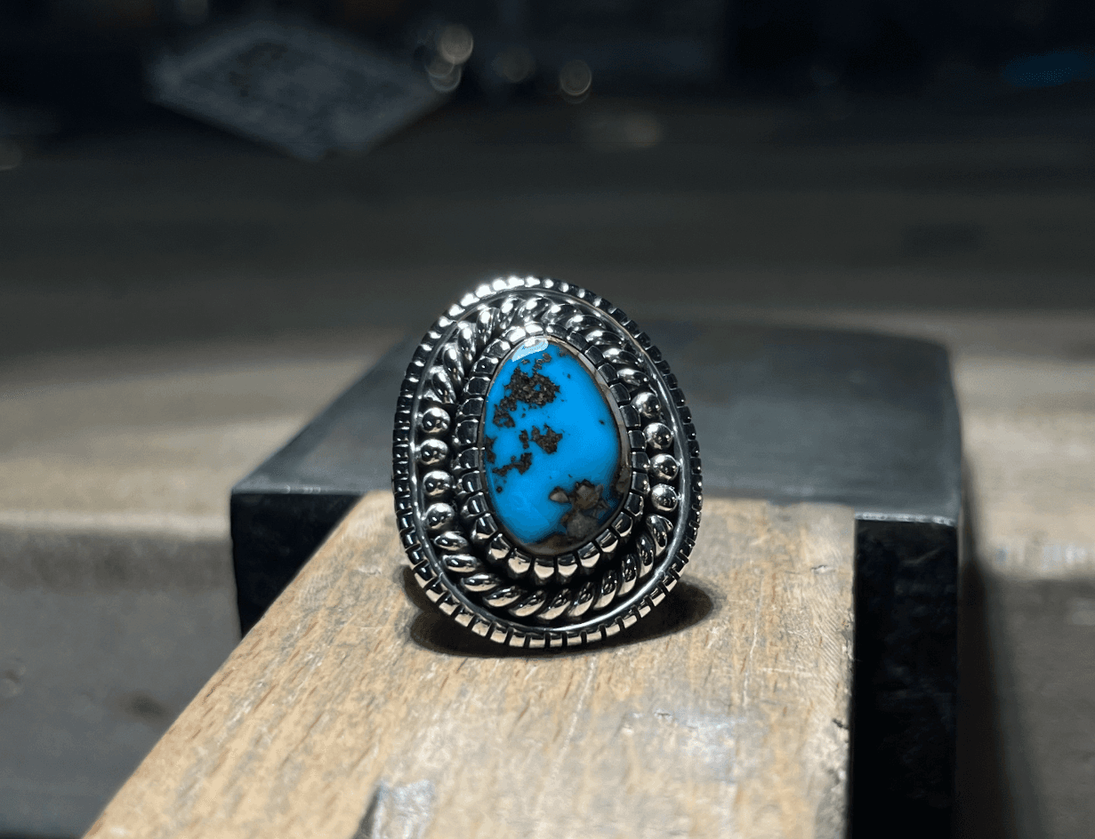 Silver ring with twisted rope and bead wire borders framing a turquoise stone