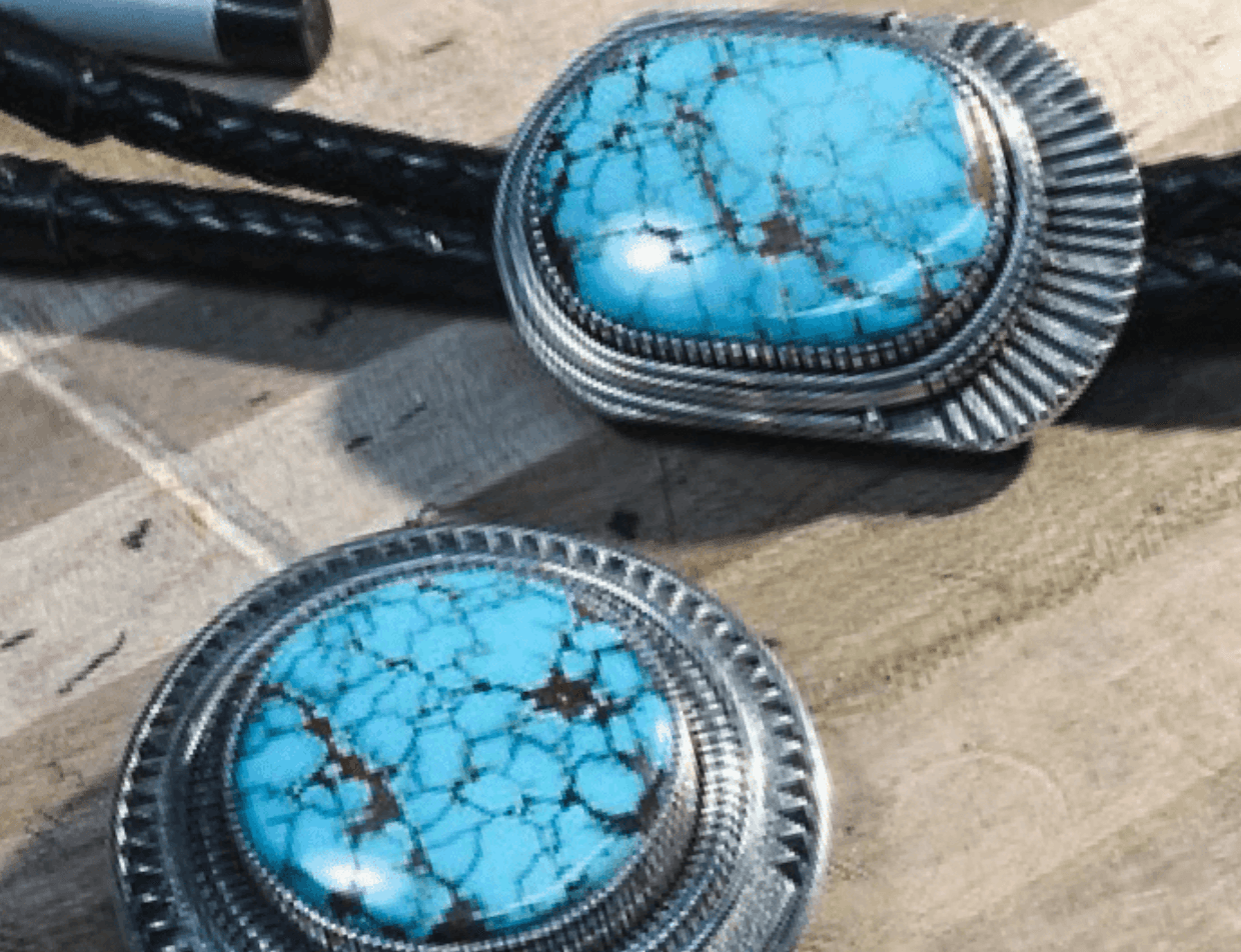 Two silver bolo tie slides with spiderweb turquoise stones on braided leather cords
